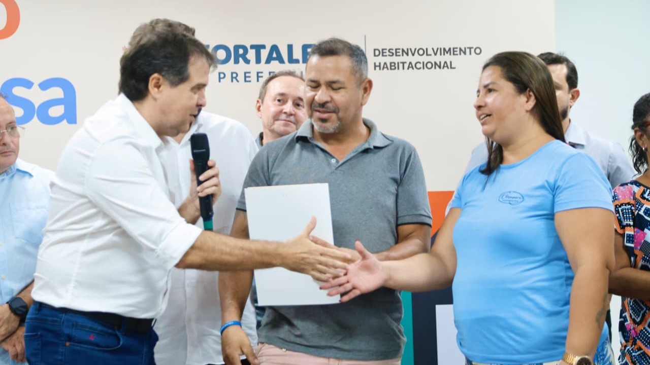 prefeito evandro cumprimenta uma mulher ao entregar o papel da casa para ela